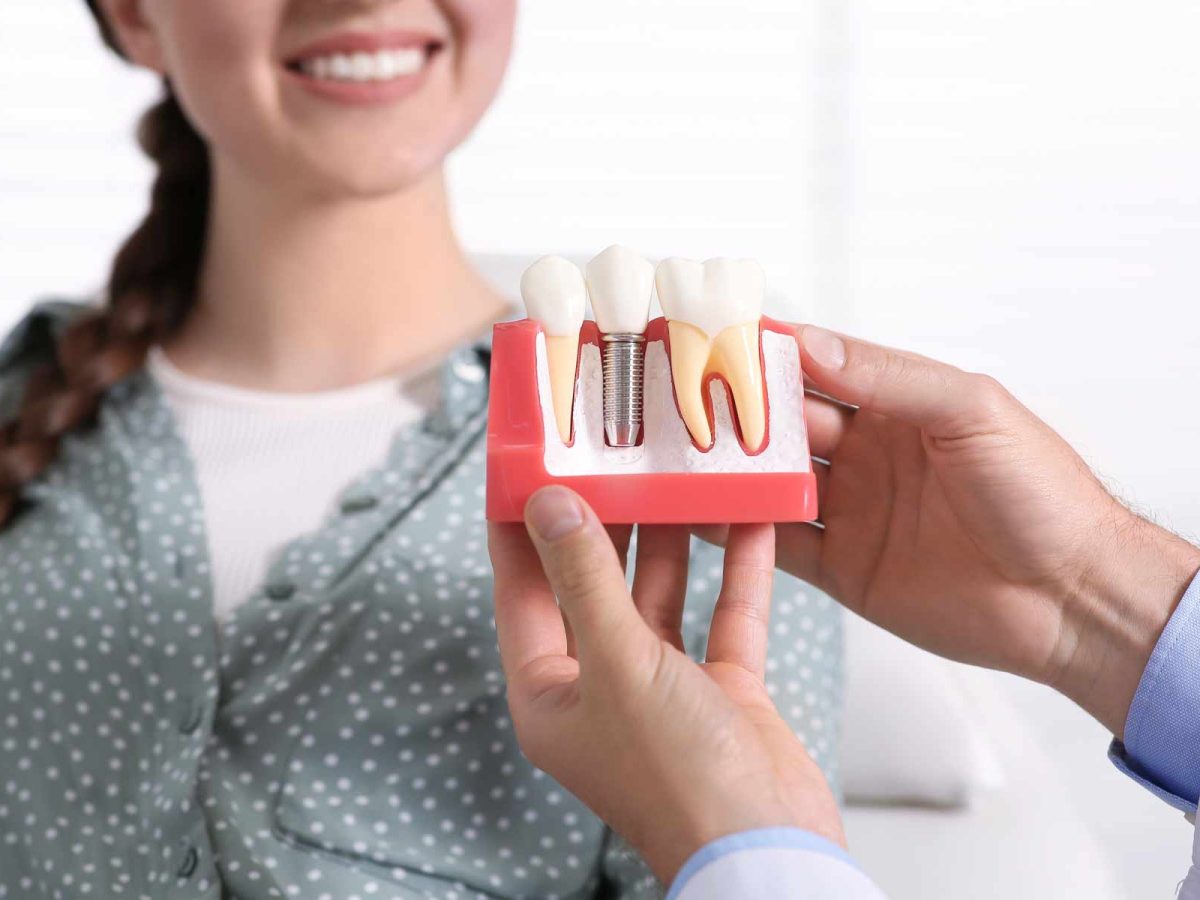 bettercare-dentist-showing-dental-implant-model-to-patient
